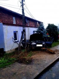 Zdjęcie kolorowe, przedstawiające samochód BMW i uszkodzony słup oraz ogrodzenie.