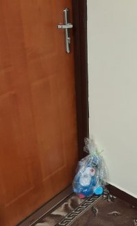 Zdjęcie kolorowe, przedstawiające prezent pozostawiony pod drzwiami.