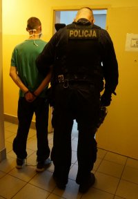 Zdjęcie kolorowe, przedstawiające policjntów o osobą zatrzymaną.