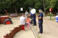 Zdjęcie kolorowe, przedstawiające policjantów i dzieci w parku.