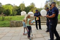 Zdjęcie kolorowe, przedstawiające policjantów i dzieci w parku.