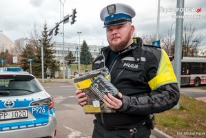 Zdjęcie przedstawiające policjanta trzymającego prezenty dla uczestników.