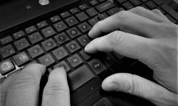 Zdjęcie przedstawiające dłonie oraz klawiaturę komputera.