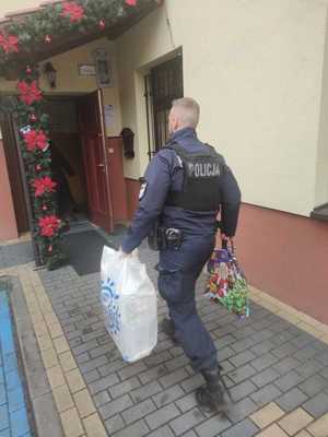 Zdjęcie przedstawiające policjanta niosącego prezenty.
