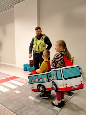 Zdjęcie przedstawiające policjanta i dzieci bawiące się mobilnym misteczkiem.