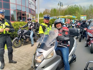 Zdjęcie przedstawiające policjantów oraz motocyklistę otrzymującego apteczkę.