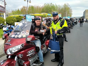 Zdjęcie przedstawiające policjanta oraz motocyklistę otrzymującego apteczkę.