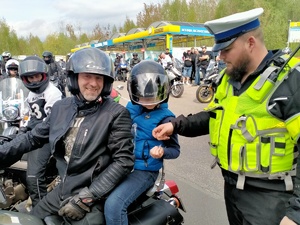 Zdjęcie przedstawiające policjanta oraz pasażera motocyklisty otrzymującego odblask.