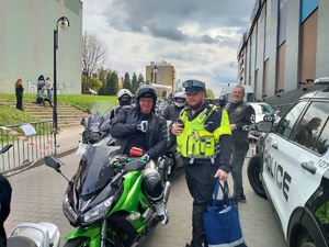 Zdjęcie przedstawiające policjanta oraz motocyklistę otrzymującego apteczkę.